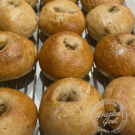 A tray of Roasted Garlic Herb Sourdough Bagels cooling on a wire rack